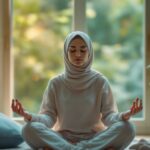 امرأة ترتدي الحجاب تمارس التأمل في وضعية اللوتس، مما يعكس تخفيف القلق والتوتر.
